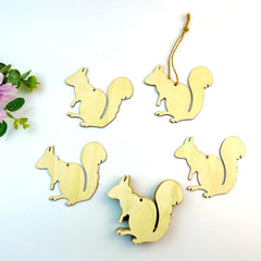Gold squirrel-shaped ornaments on a white background with greenery.