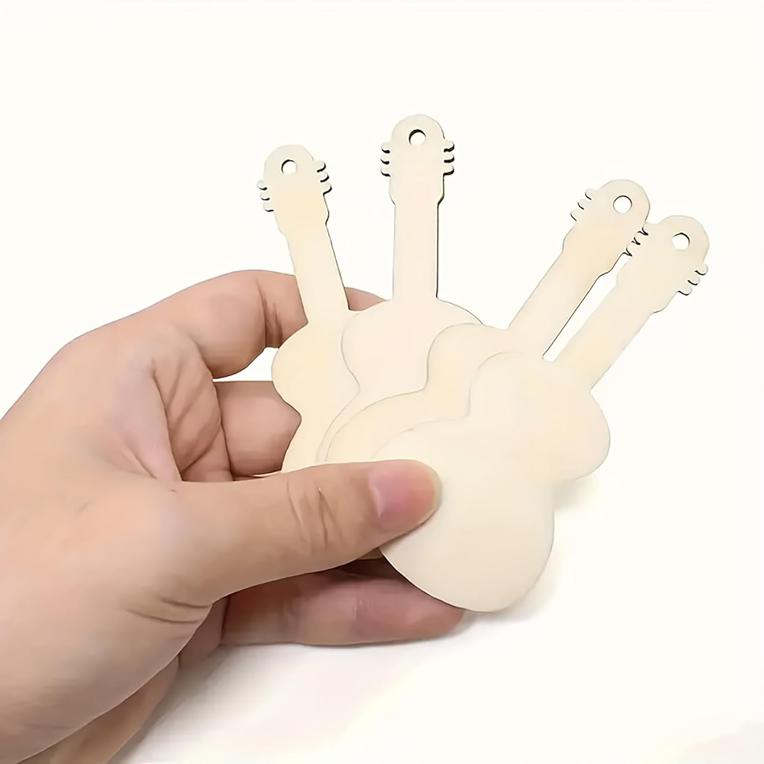 Hand holding a beige plastic tool shaped like a guitar with multiple strings on a white background
