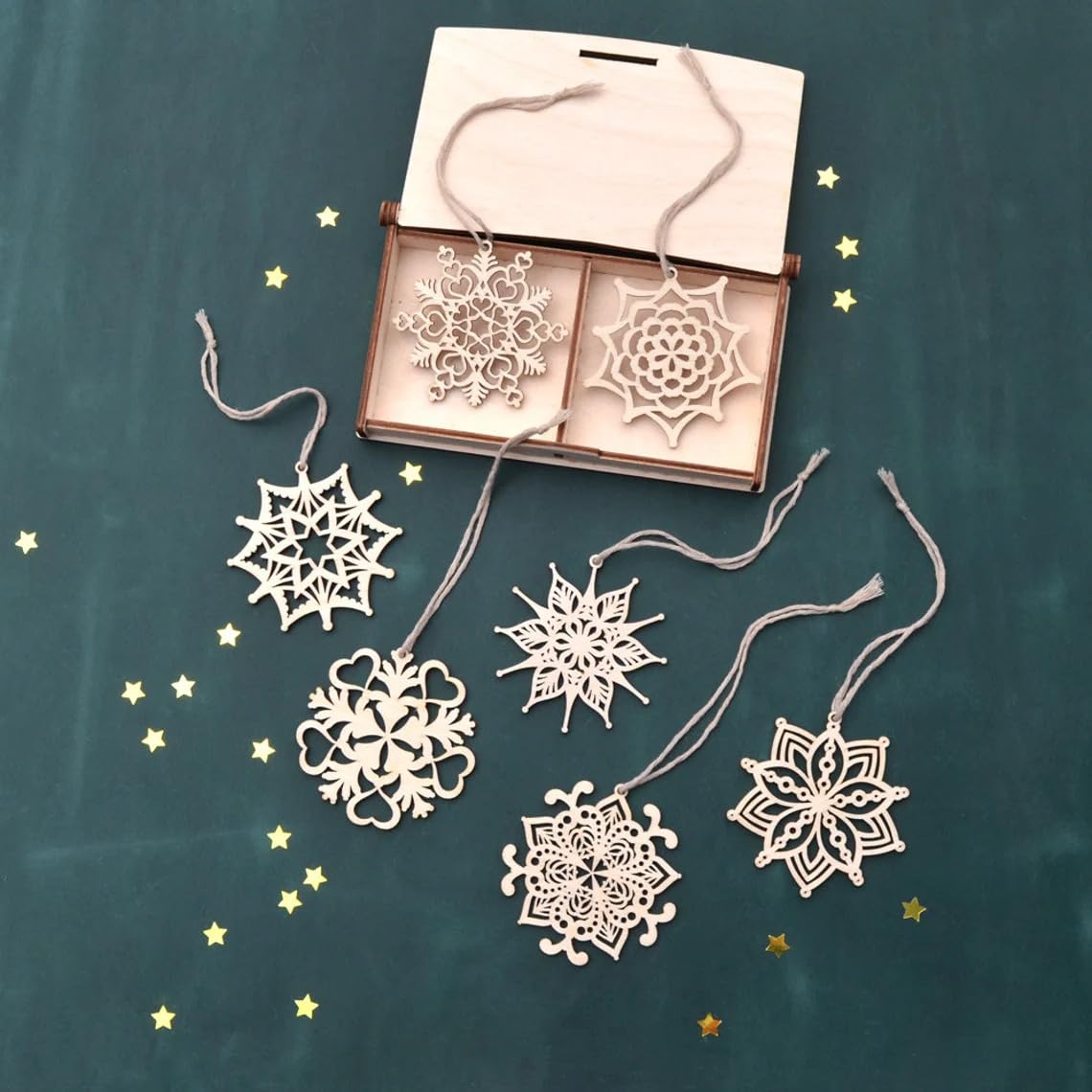 Decorative snowflake ornaments with a box on a dark green background with gold stars.