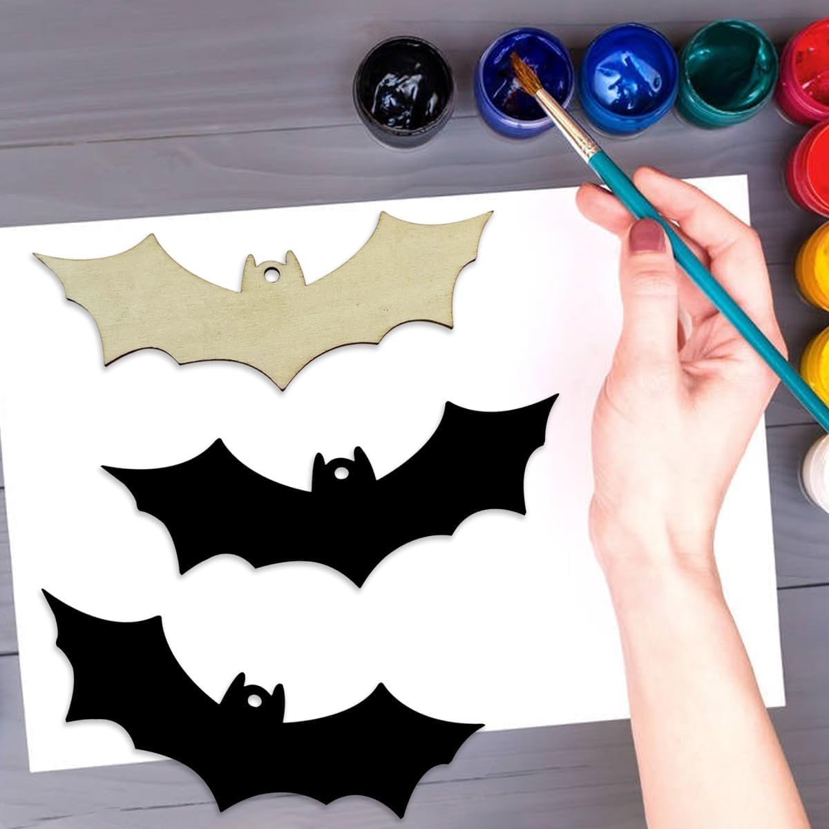 Hand painting bat shapes on paper with watercolor paints.