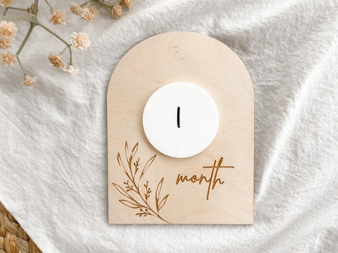 Wooden baby milestone card with a white candle and '1 month' text on a white fabric background.