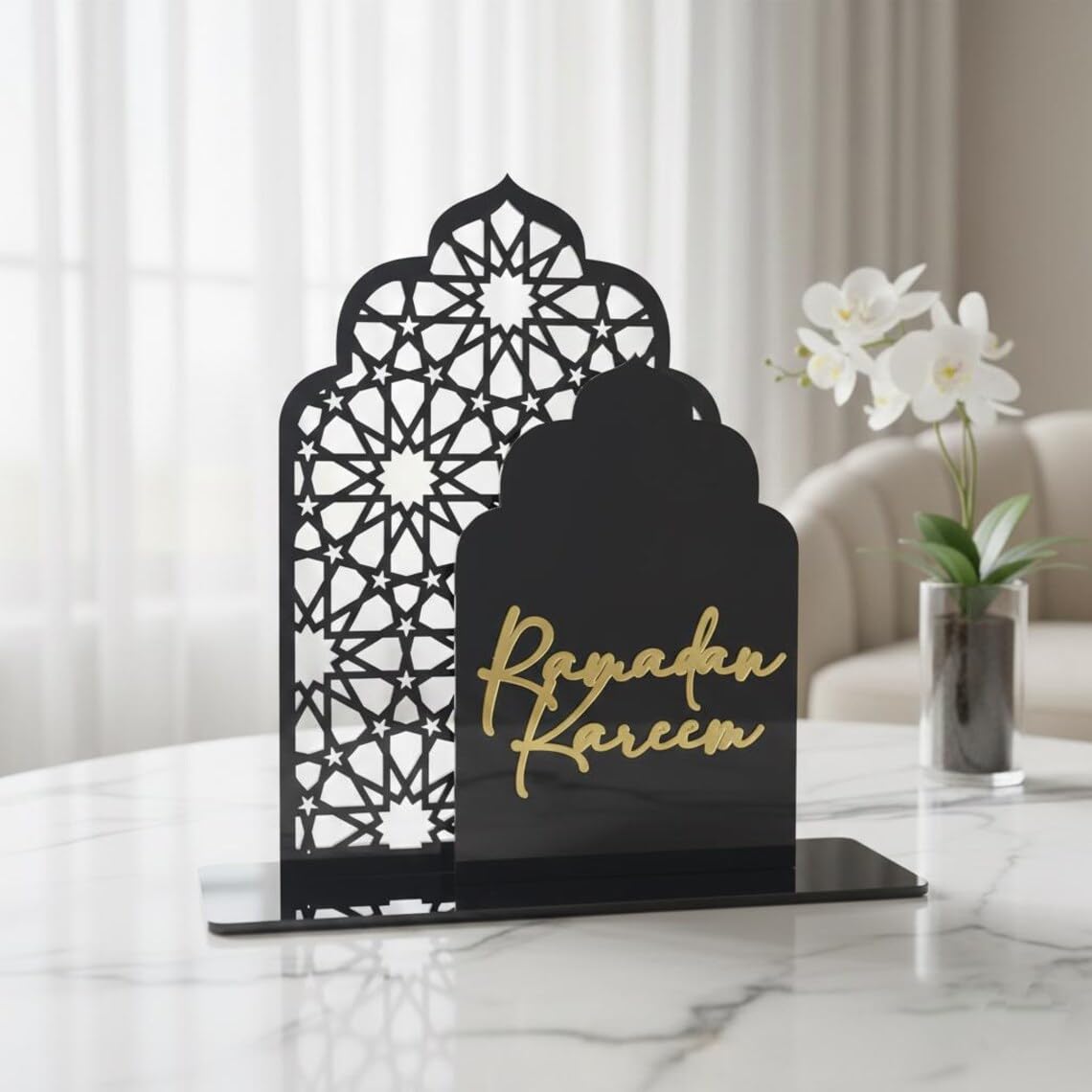 Decorative black metal stand with 'Ramadan Kareem' text on a marble surface.