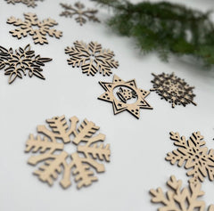Wooden snowflake and star decorations on a white surface with a blurred green background