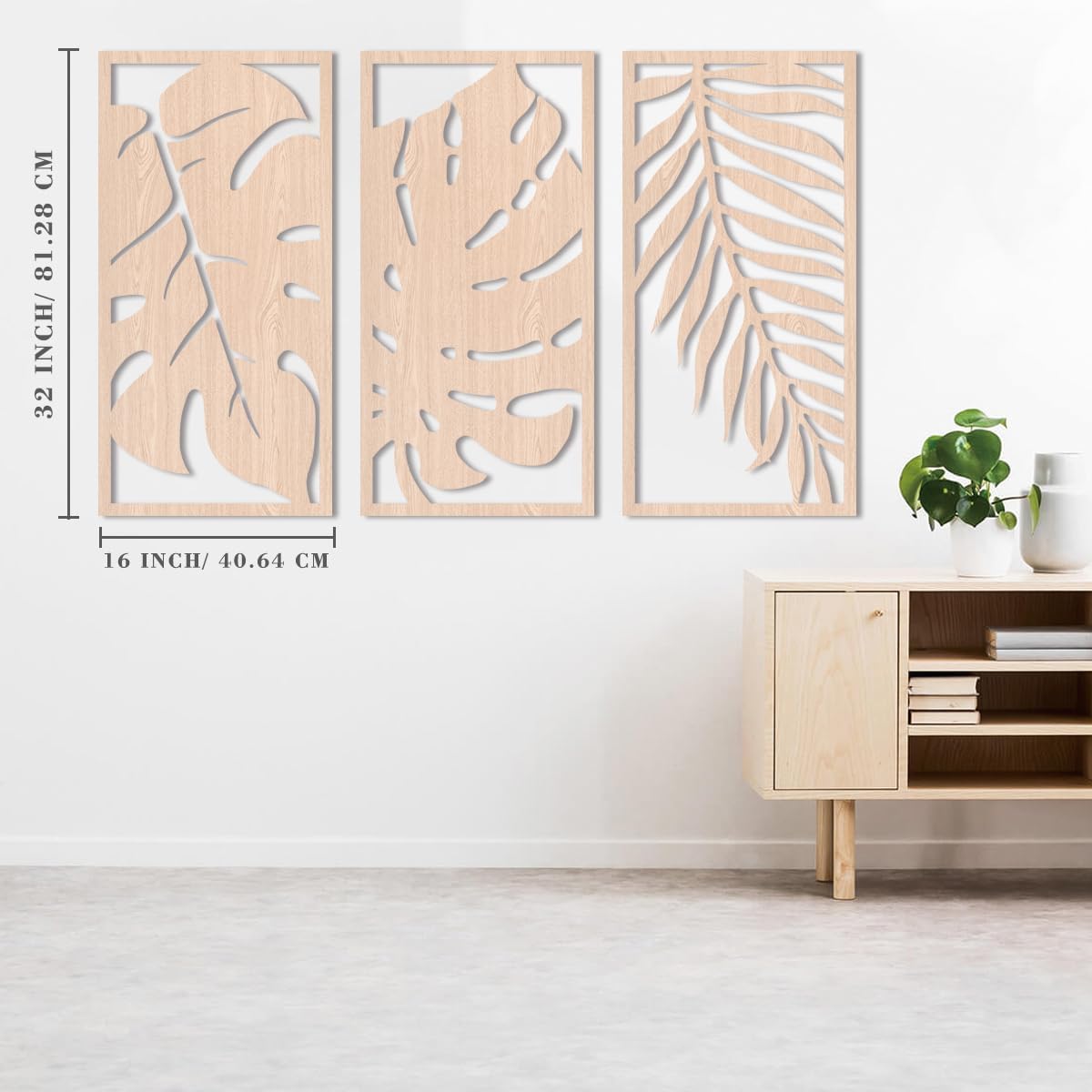 Three wooden wall art panels with leaf patterns on a white wall above a wooden cabinet.