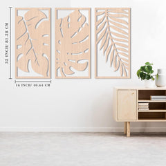 Three wooden wall art panels with leaf patterns on a white wall above a wooden cabinet.