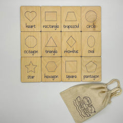 Wooden shape blocks with labels and a drawstring bag on a light gray background