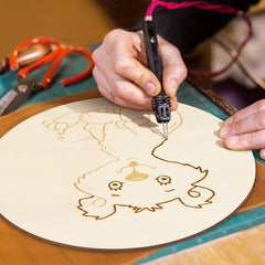 Person using a laser cutting machine to create a design on a wooden board.