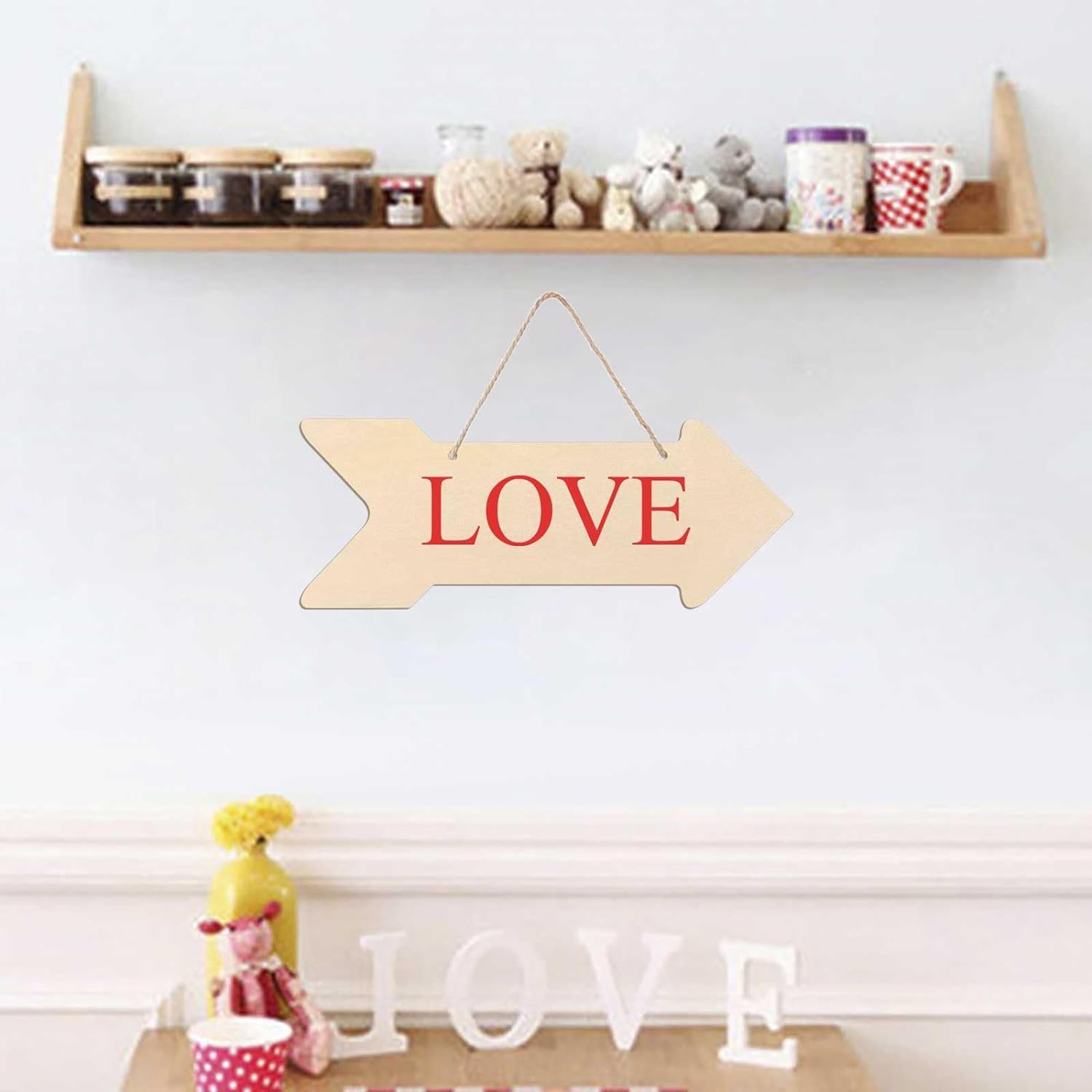 Wooden 'LOVE' sign hanging on a wall with decorative items below.
