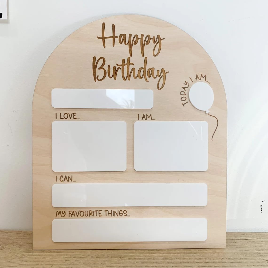 Wooden board with 'Happy Birthday' text and blank sections for writing on a white background
