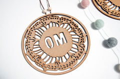 Decorative wooden pendant with 'OM' engraving on a white background