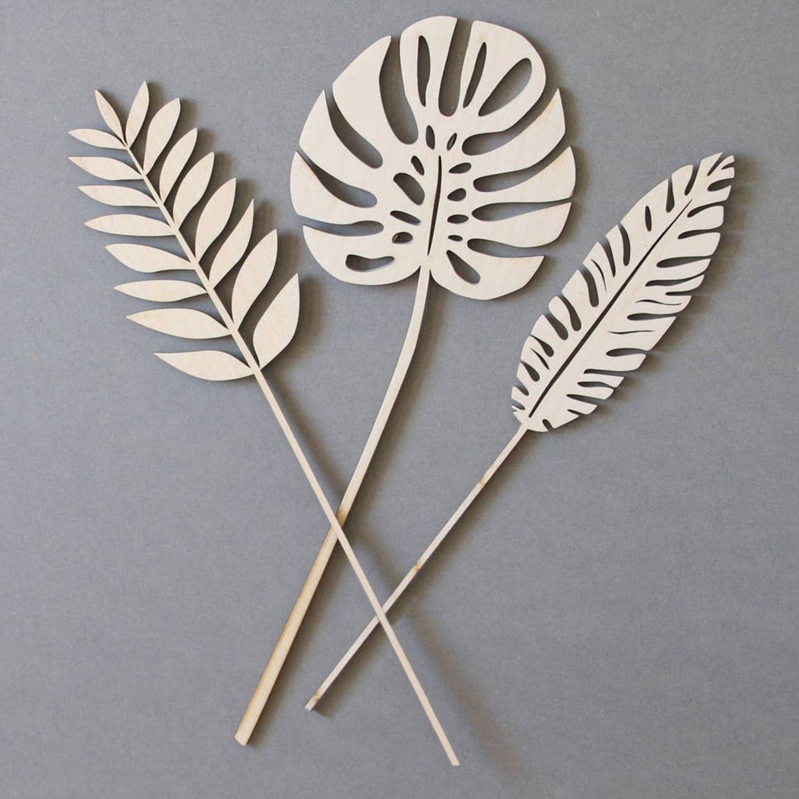 Three cut-out leaf shapes on sticks against a gray background