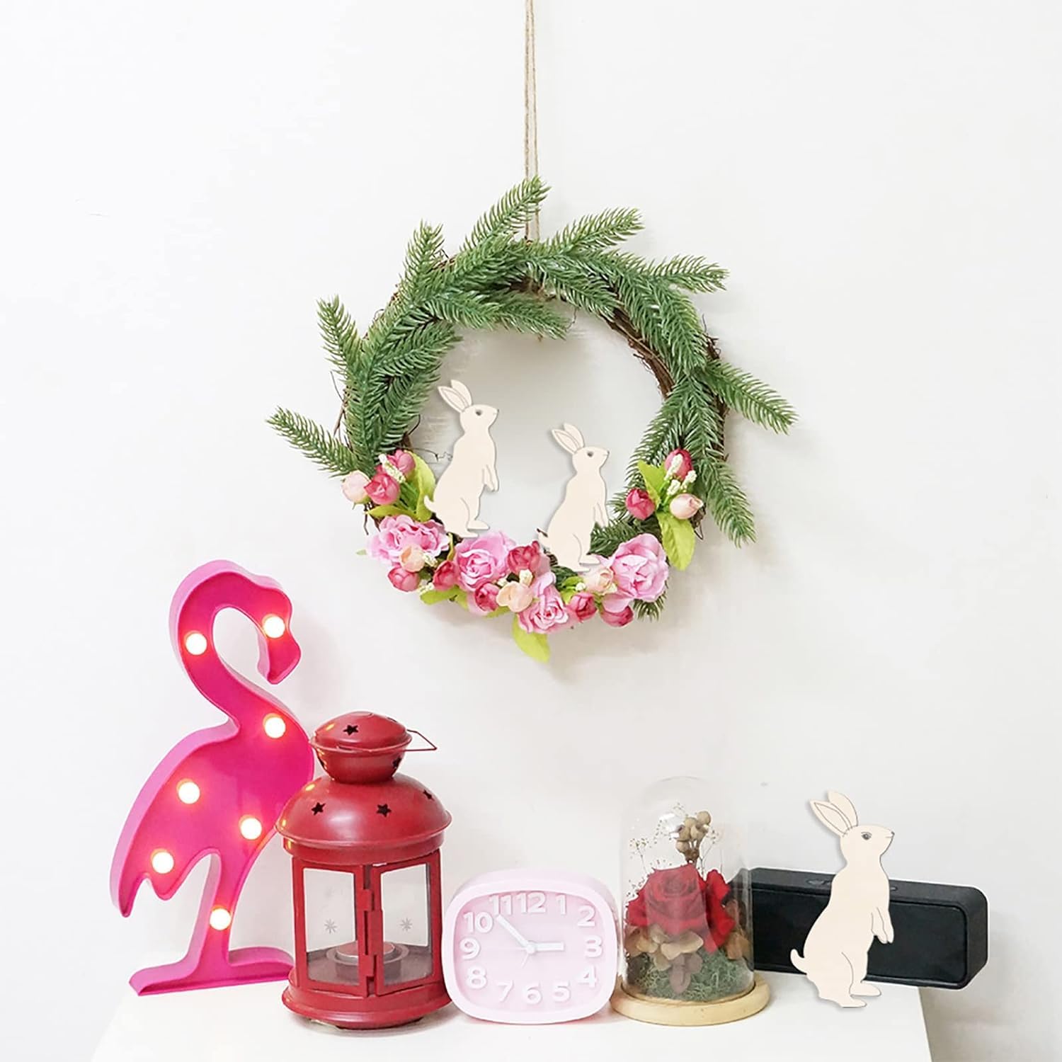 Decorative wreath with flowers and bunnies, pink flamingo light, red lantern, pink clock, and rabbit figurine on a white background.