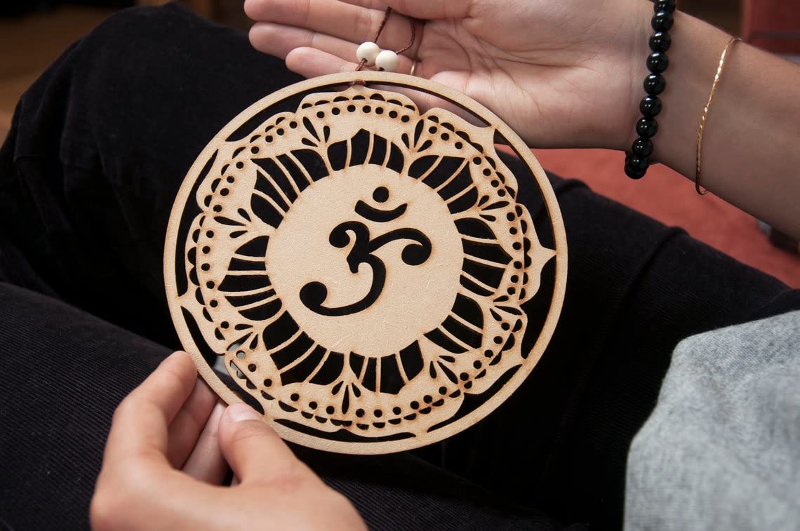 Decorative wooden pendant with Om symbol held by hands