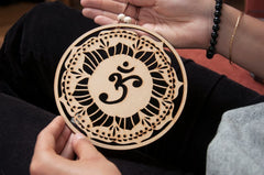 Decorative wooden pendant with Om symbol held by hands