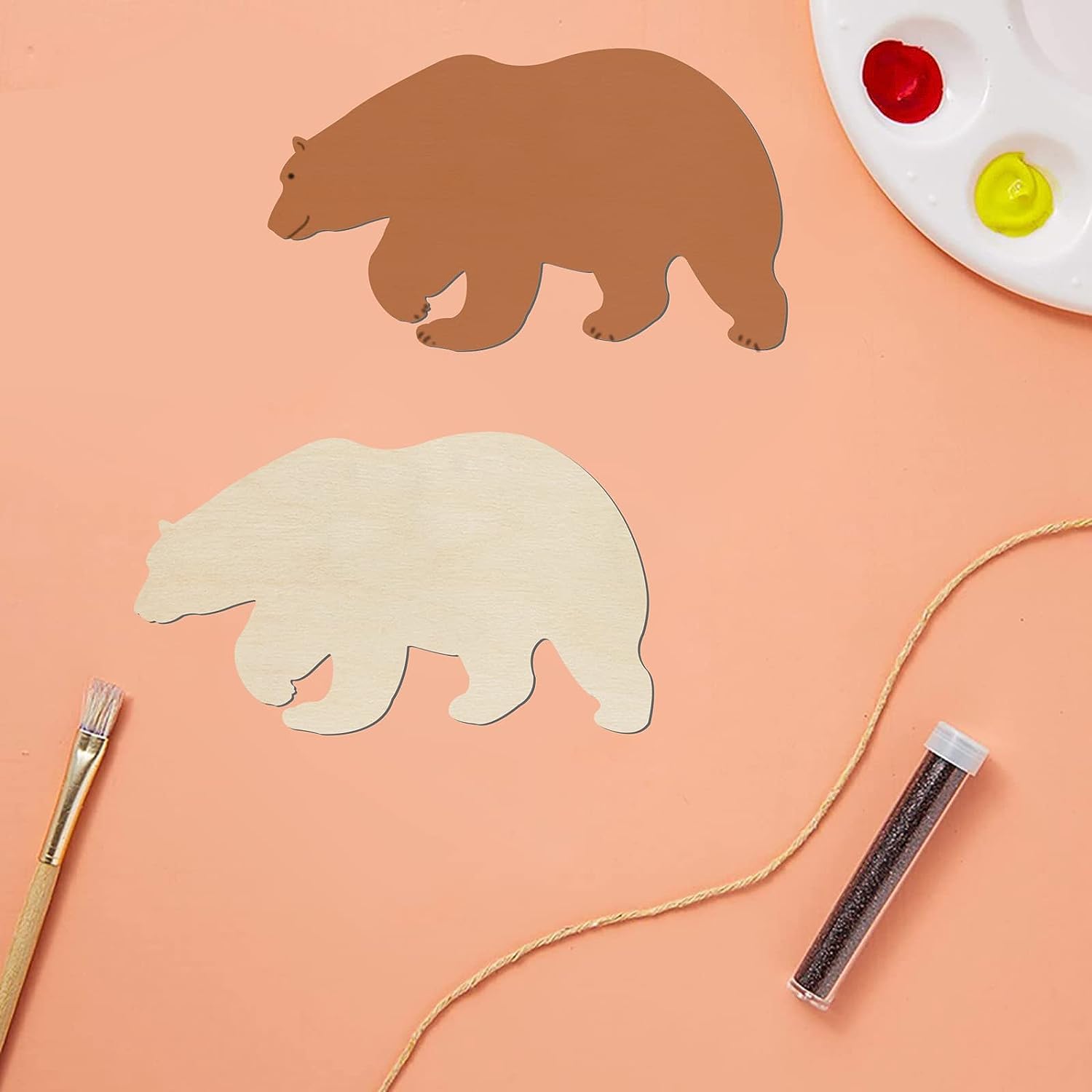 Two bear-shaped cutouts on a peach-colored surface with painting supplies.