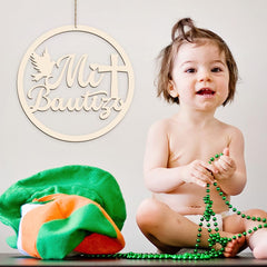 Child holding green beads with a decorative sign reading 'Mi Bautizo' in the background