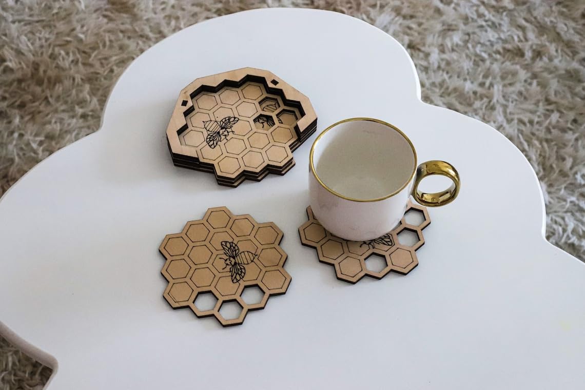 Hexagonal wooden coasters with bee design on a white surface with a cup.