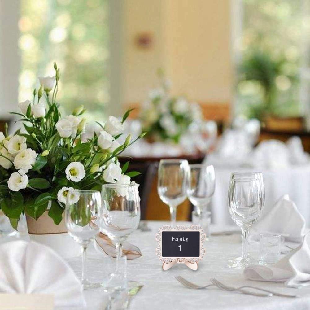 Set table with white flowers, glasses, and a table number card in a blurred indoor setting.