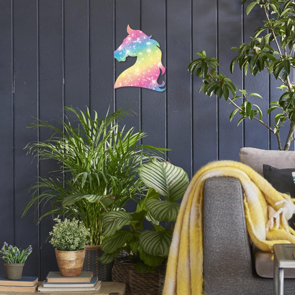 Colorful unicorn wall art on a dark wooden panel wall with plants and a gray chair.