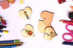 Heart-shaped wooden toys with colorful markers and scissors on a white background
