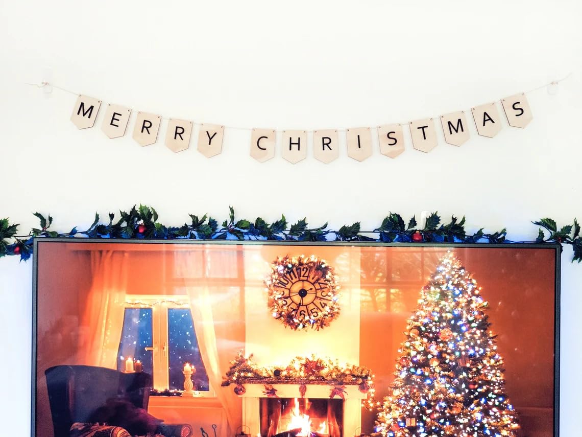 Decorated room with Christmas tree, fireplace, and 'Merry Christmas' banner.