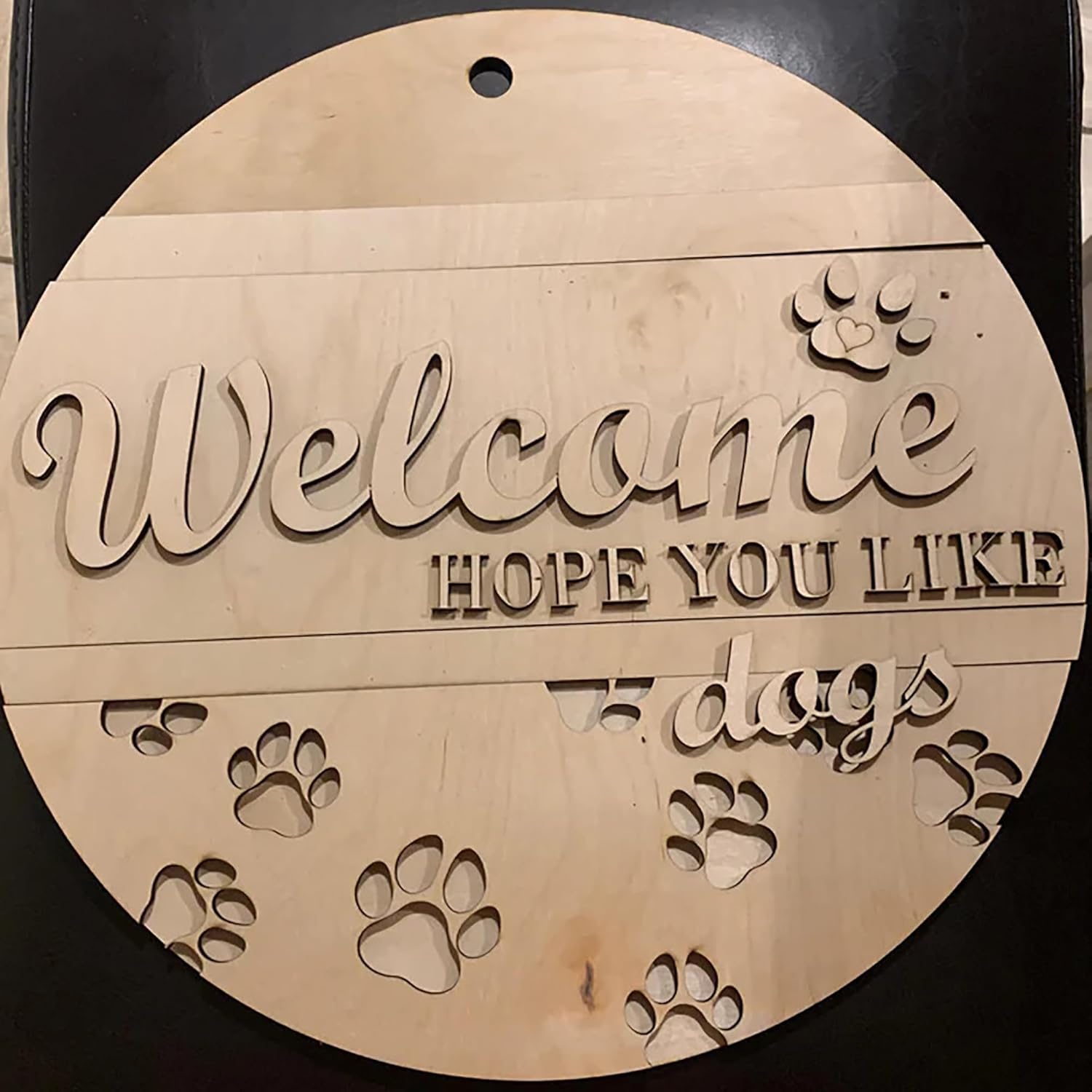Wooden round sign with 'Welcome hope you like dogs' text and paw prints on a black background