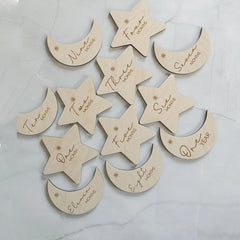 Wooden moon and star-shaped ornaments with milestone markings on a light background