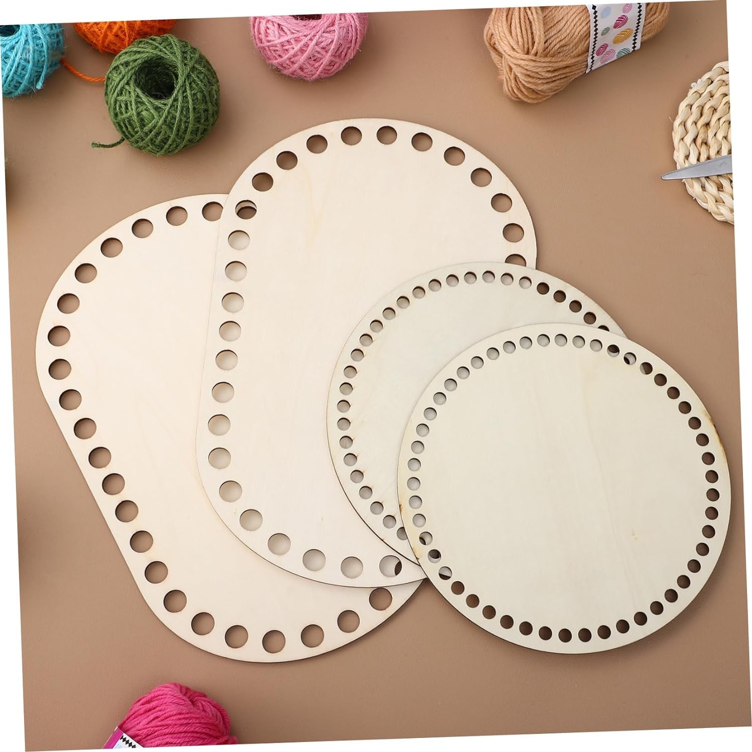 Three wooden lace-making boards with holes on a brown surface with yarn balls.