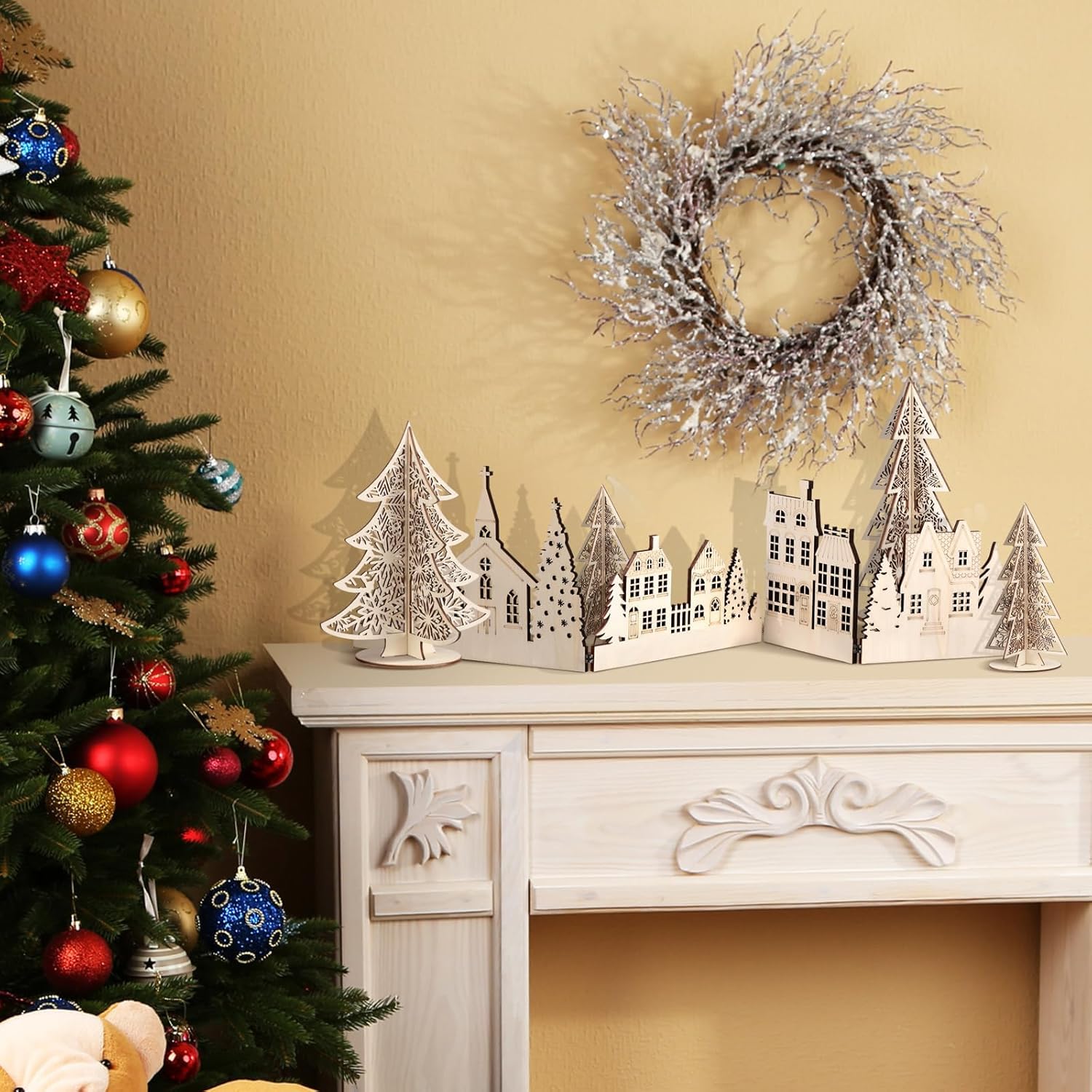 Decorative Christmas scene with a tree, wreath, and small village on a mantelpiece.
