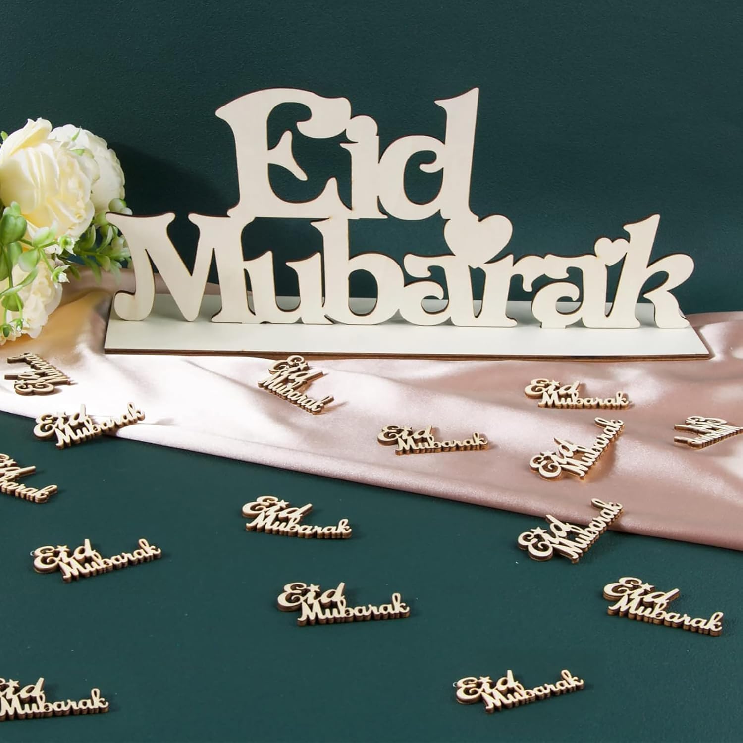 Decorative 'Eid Mubarak' signs on a dark green background with white flowers.