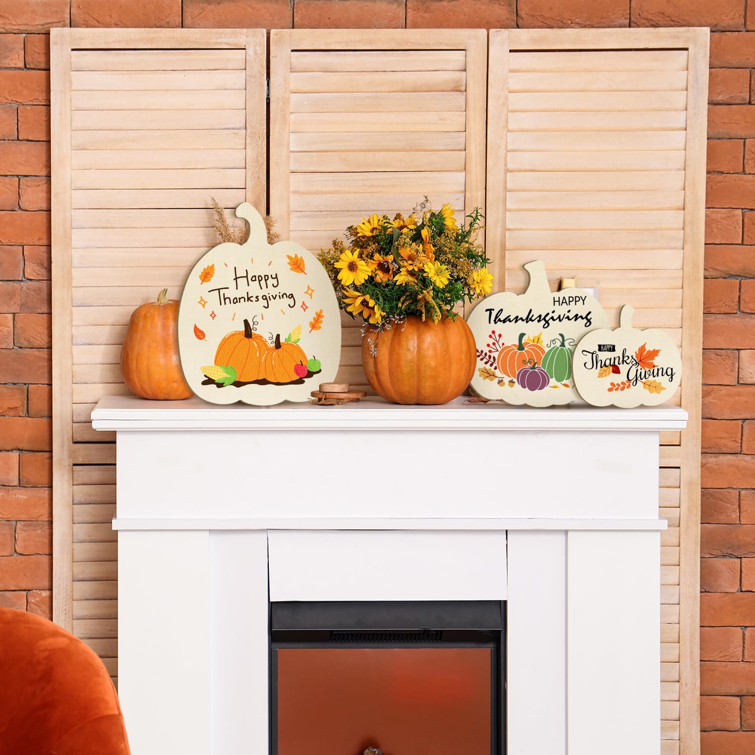Decorative Thanksgiving mantel with pumpkins, signs, and flowers against a brick wall.