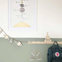 Children's room with wall decorations including a planet chart, rainbow, and teepee, with a backpack hanging on a hook.