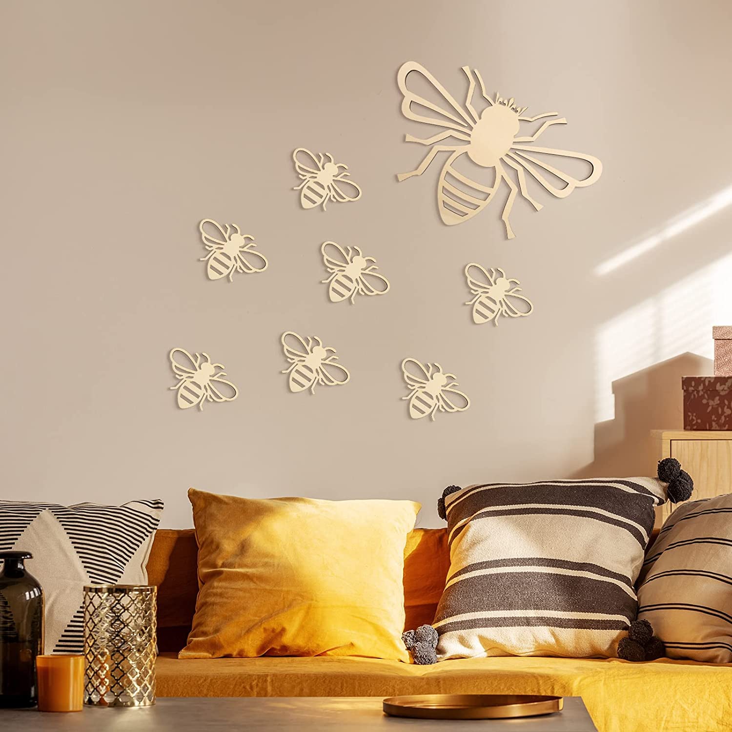 Decorative bee wall stickers on a wall above a sofa with striped cushions.
