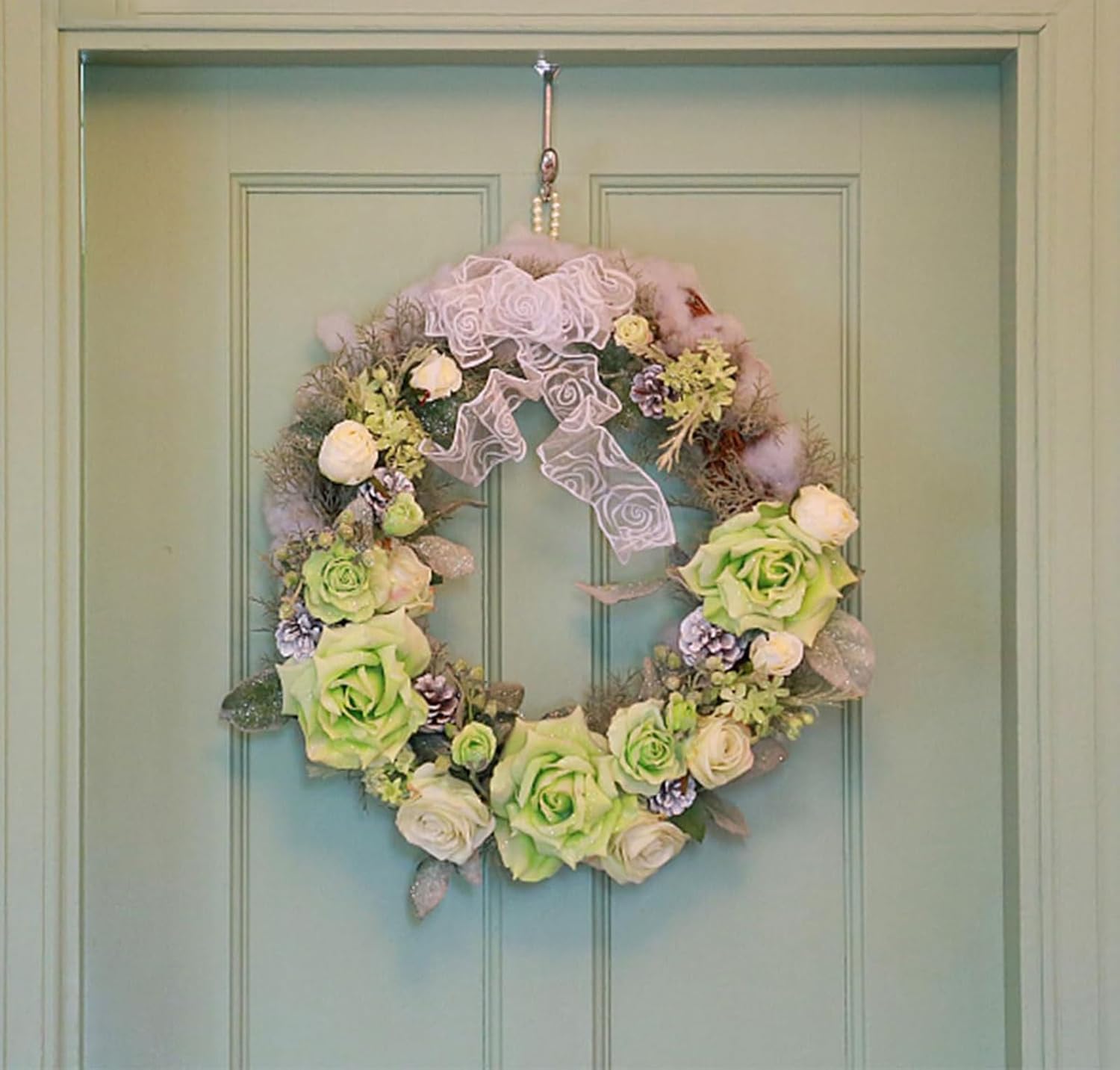 Floral wreath with green and white flowers on a light blue door