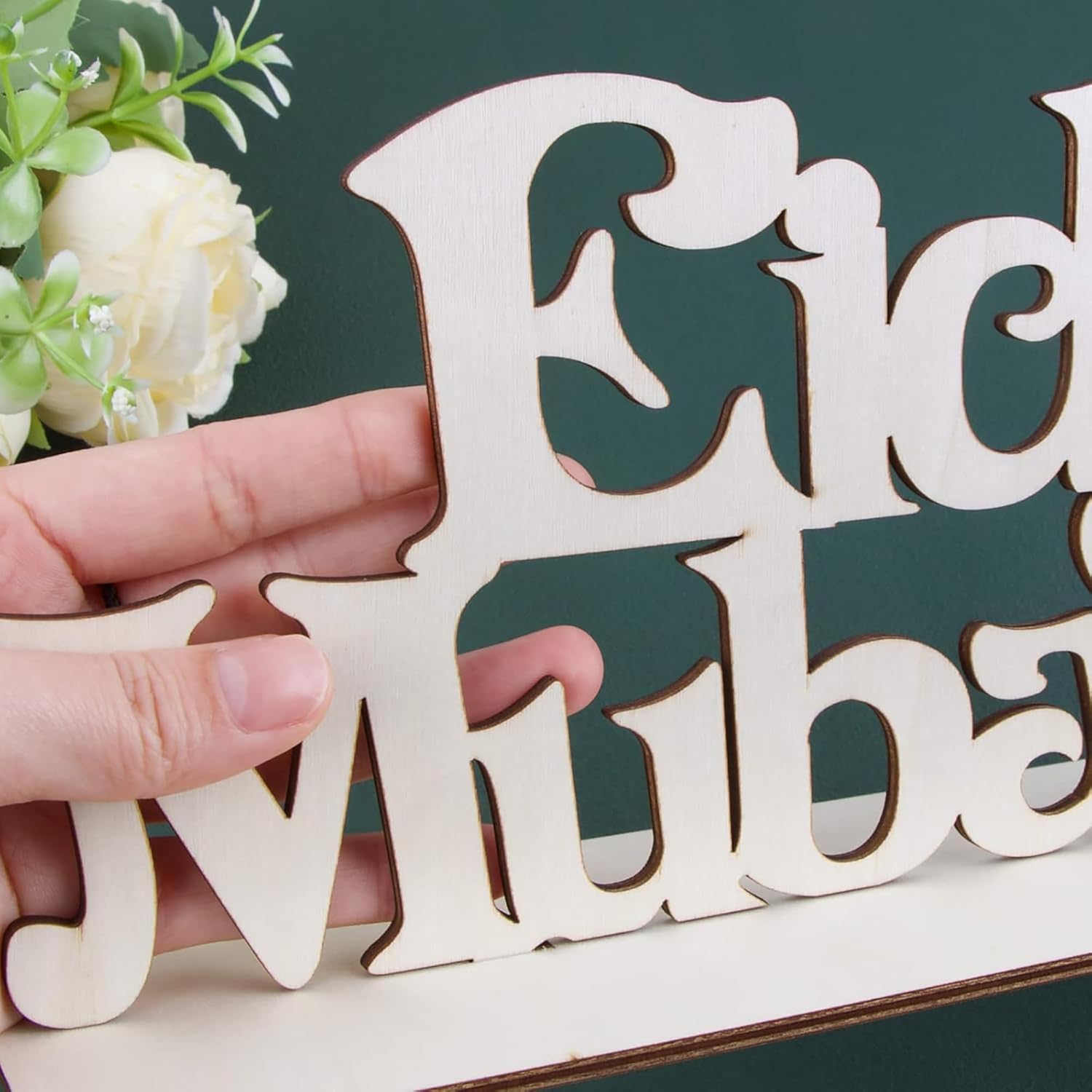 Wooden letter 'E' held by a hand with a decorative background