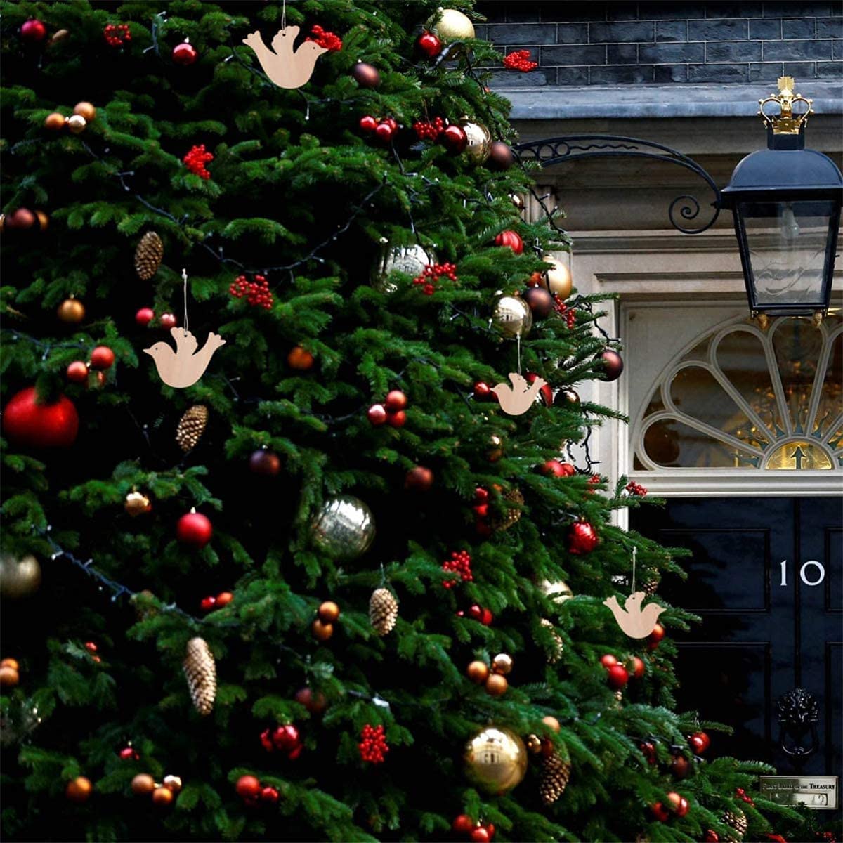 Decorated Christmas tree with ornaments in front of a building with number 10 on the door.