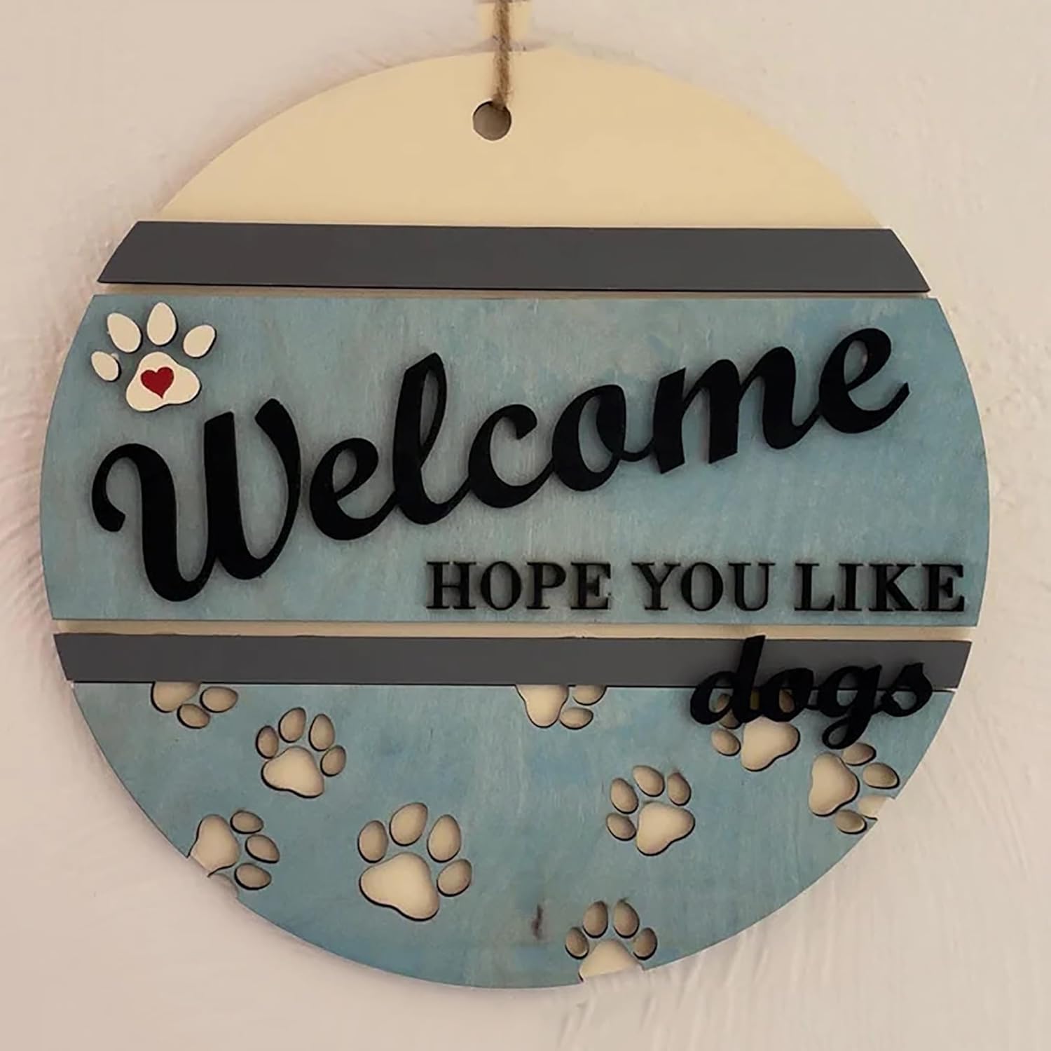 Round wooden sign with 'Welcome Hope You Like Dogs' text and paw prints on a light background