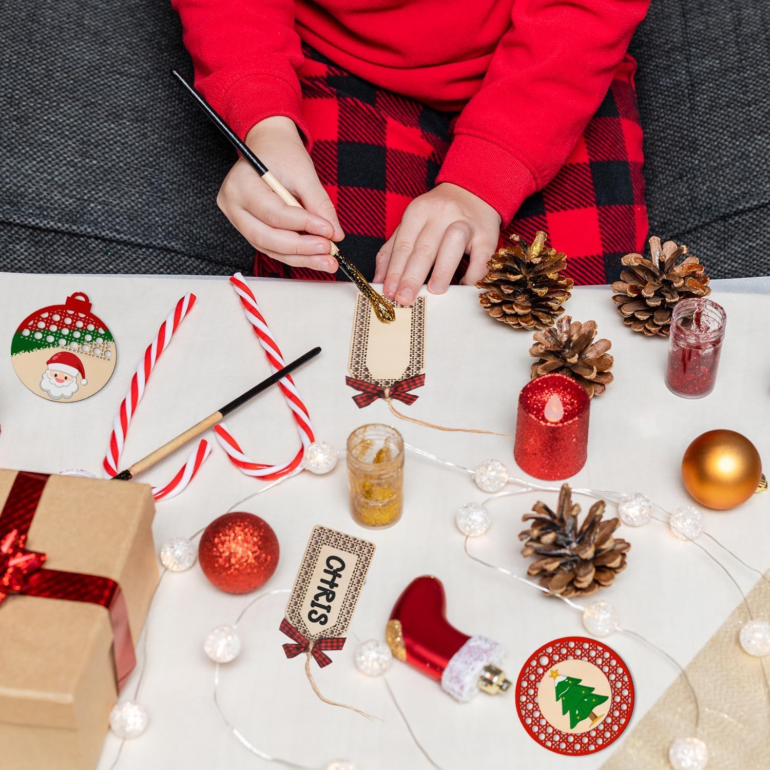 Person decorating Christmas ornaments on a table with festive items.