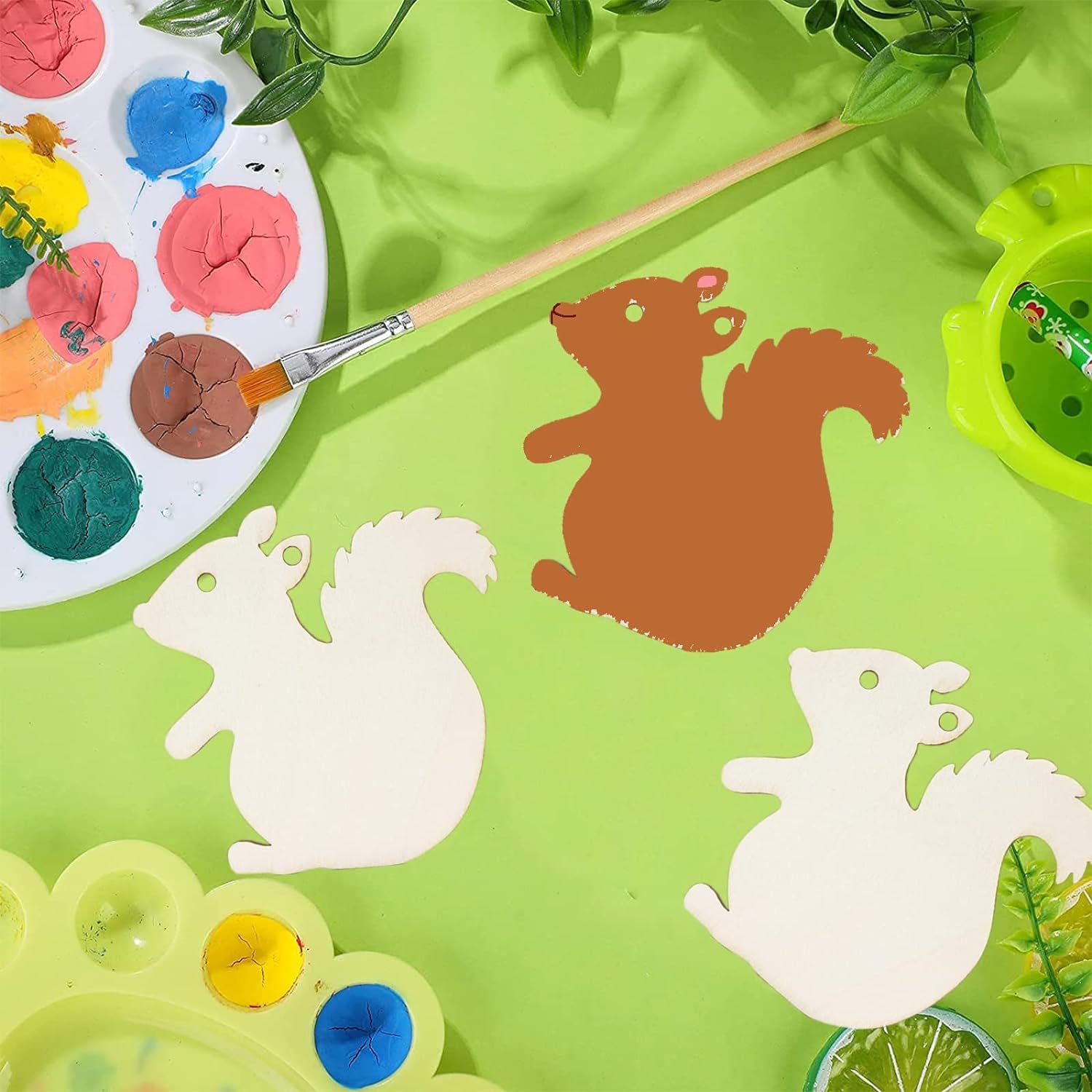 Colorful paint palette with squirrel shapes and painting tools on a green background