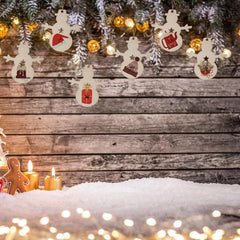 Decorative snowman ornaments on a wooden background with candles and lights.