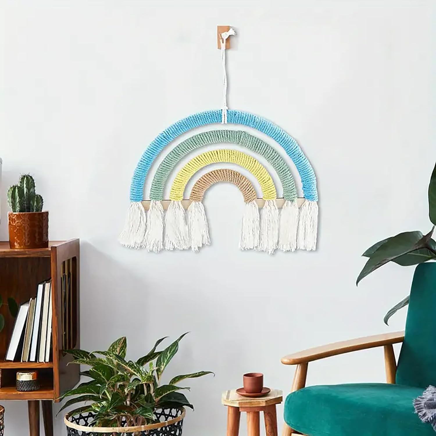 Colorful woven rainbow wall hanging in a room with plants and furniture.