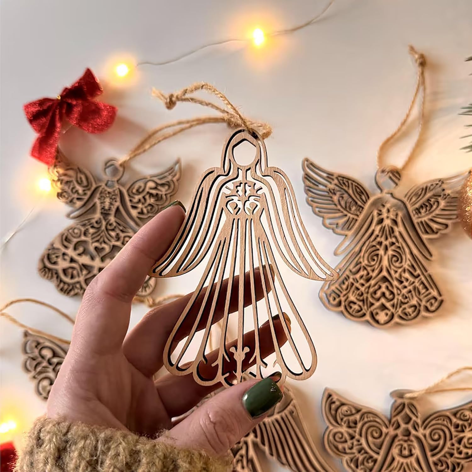 Decorative angel ornament held by a hand with string lights in the background