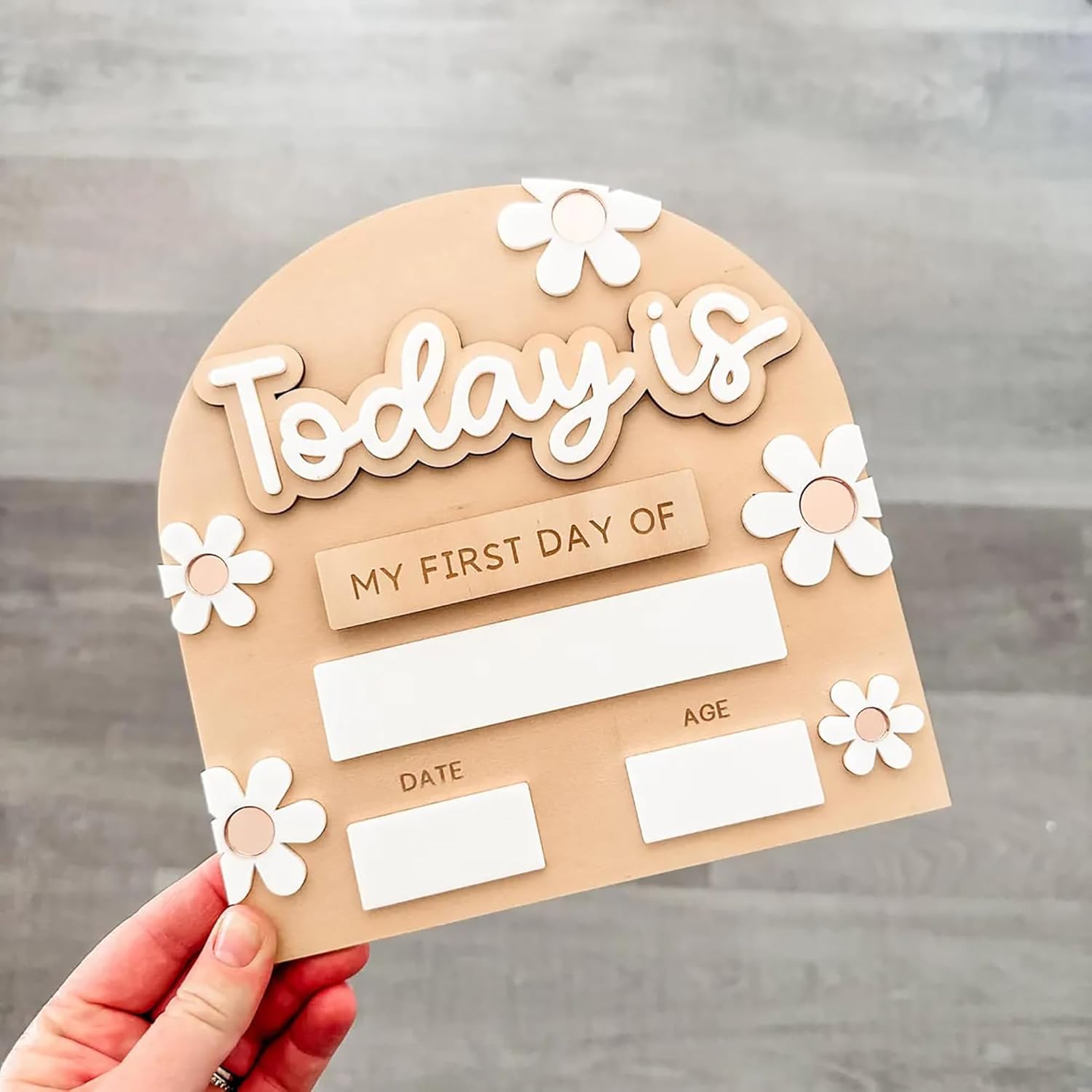 Cardboard cutout with 'Today is' and 'My First Day of' text, held against a gray background