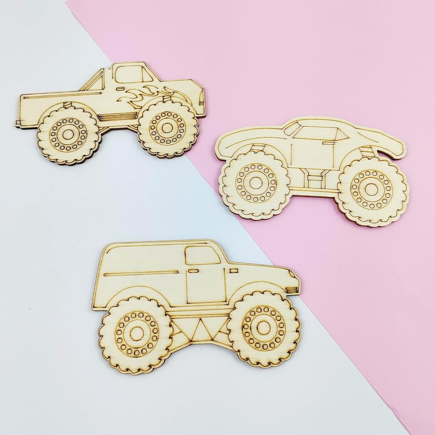 Three wooden toy truck models on a two-tone pink and white background