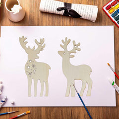 Two paper reindeer cutouts on a white sheet of paper with art supplies around.