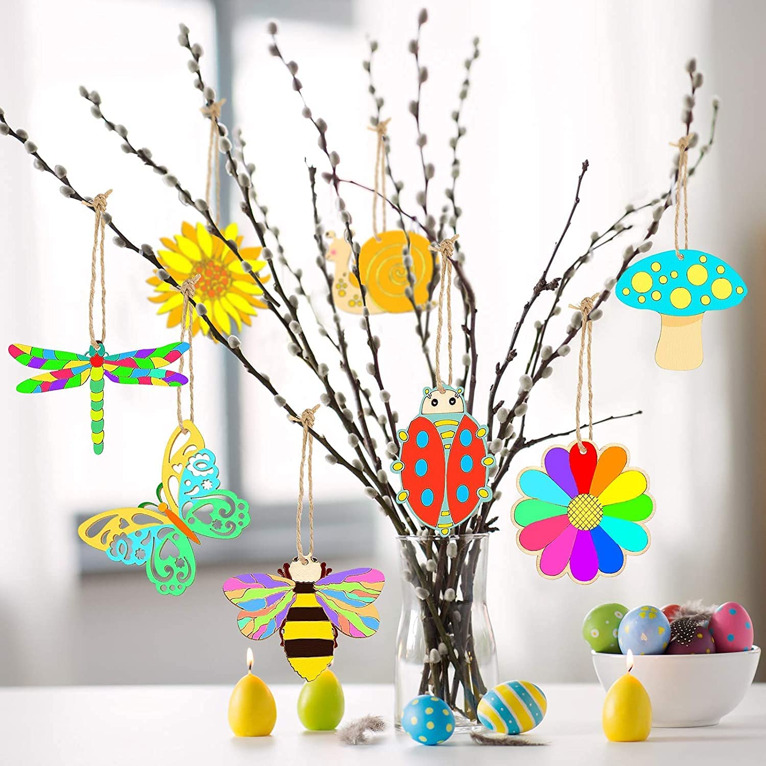 Colorful wooden ornaments hanging from branches with a blurred background