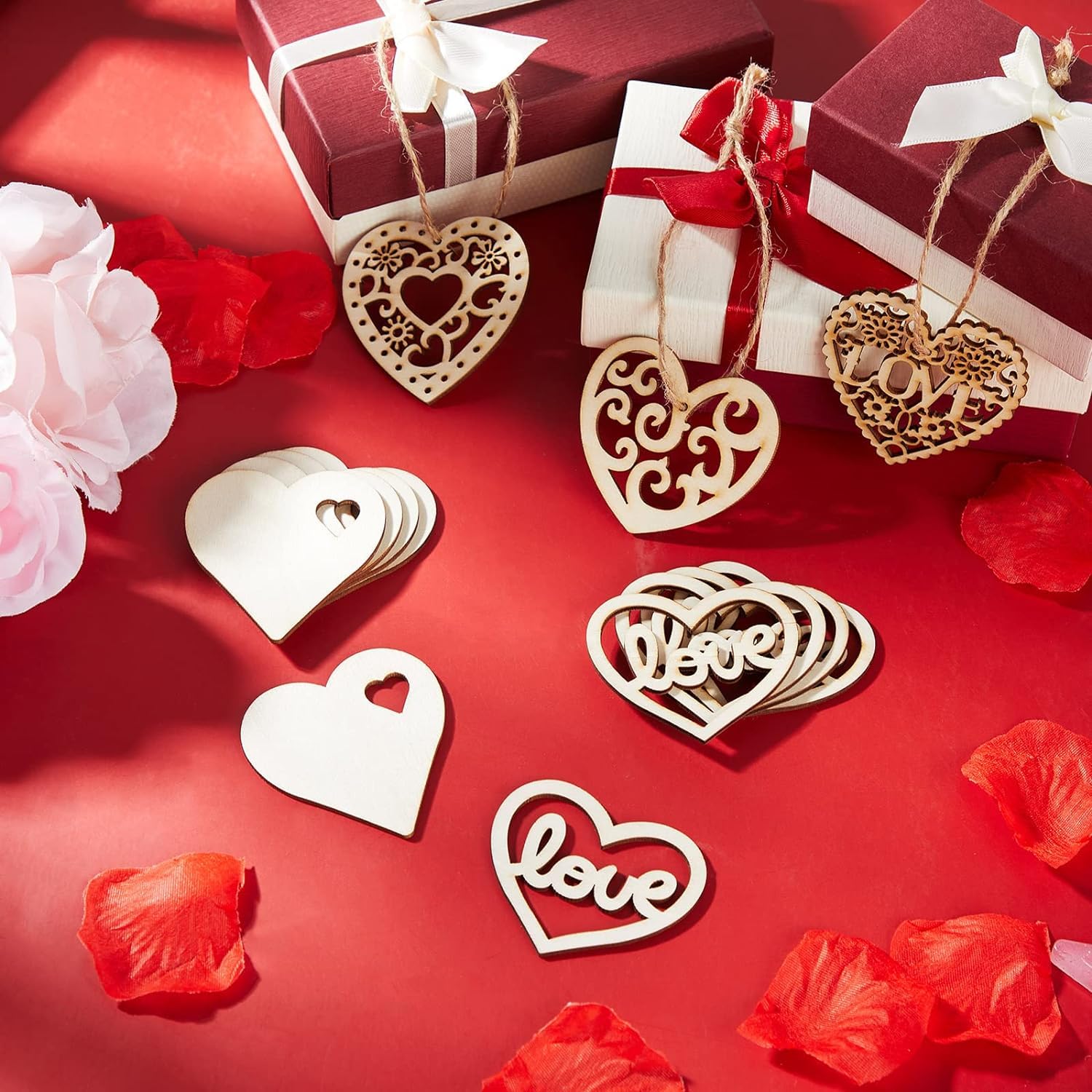 Decorative wooden hearts with 'love' on a red background with gift boxes and flowers.
