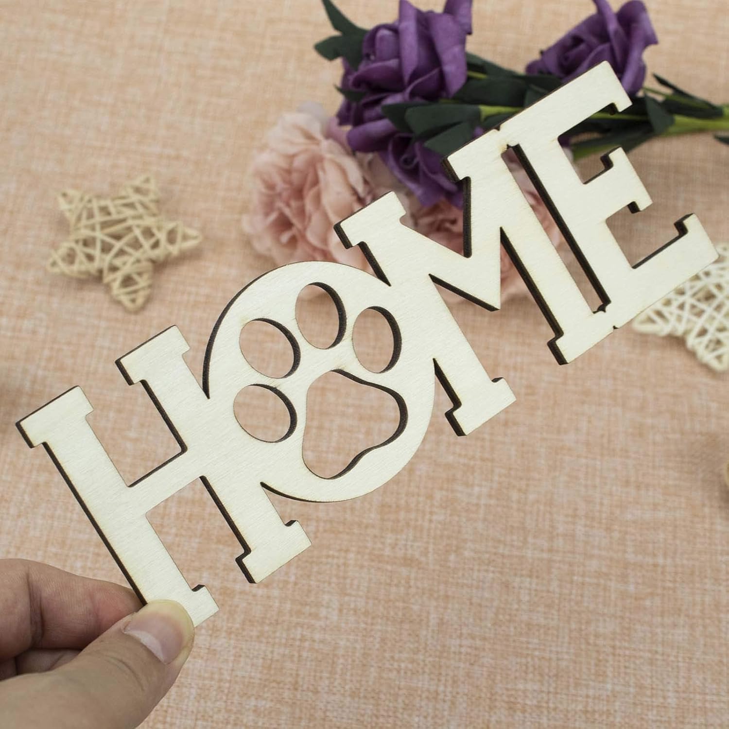Wooden decorative sign with 'HOME' and a paw print on a textured surface with flowers.