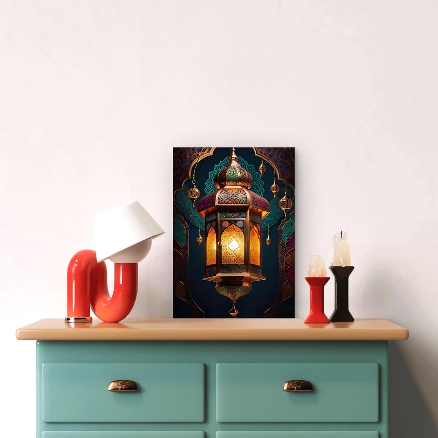 Decorative wall art of a lantern on a teal dresser with red and black candle holders.