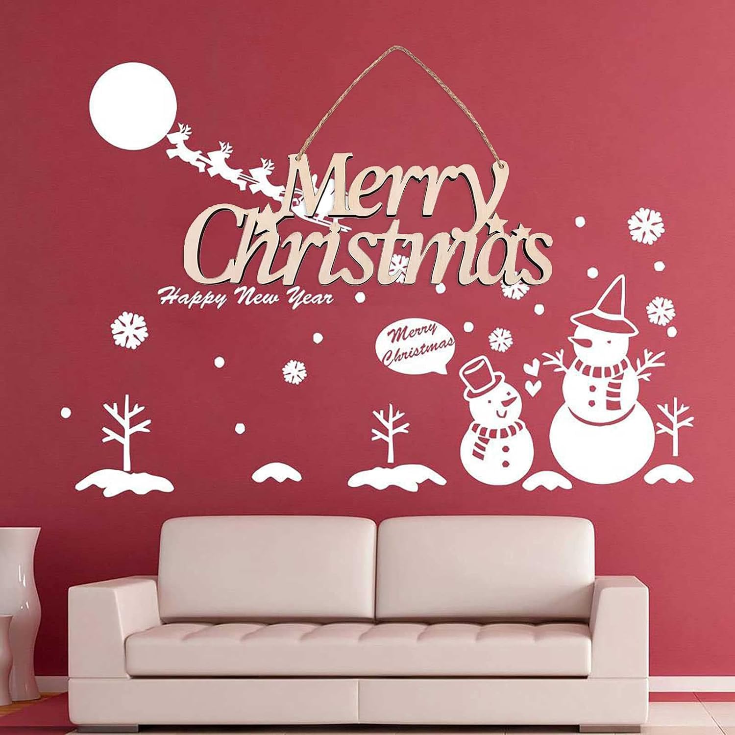 Decorative Christmas wall decal with 'Merry Christmas' and snowmen on a red wall above a beige sofa.